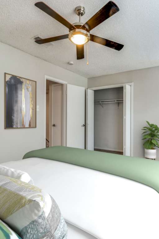 A bedroom with a bed, nightstands, and a ceiling fan.