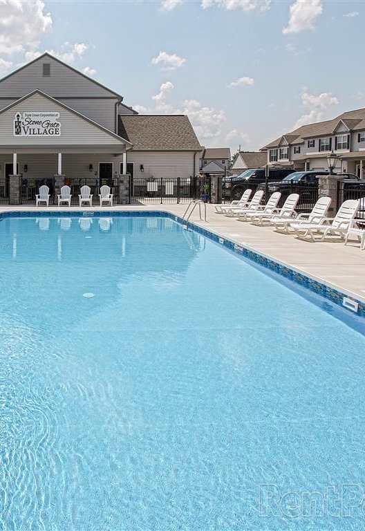 a large swimming pool with white chairs around it