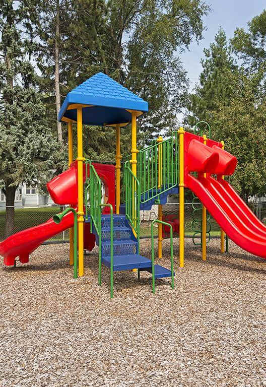 A playground with a red slide, a blue slide, and a yellow platform. at Minnehaha Manor, Oakdale, MN, 55128