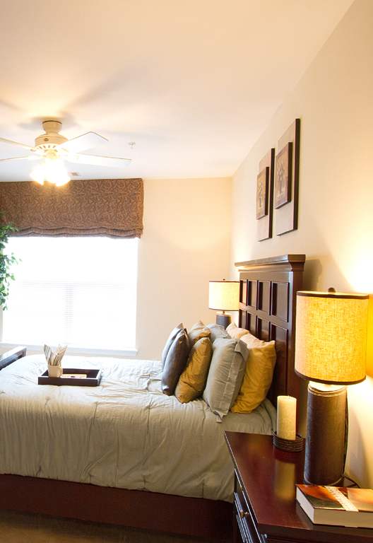 a bedroom with a bed and a dresser and a ceiling fan at The Summit at Owings Mills Apartments, Owings Mills Maryland