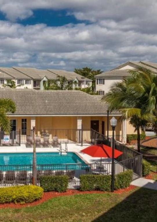 a swimming pool in front of a house with palm trees at Valencia Pointe, Miami, Florida
