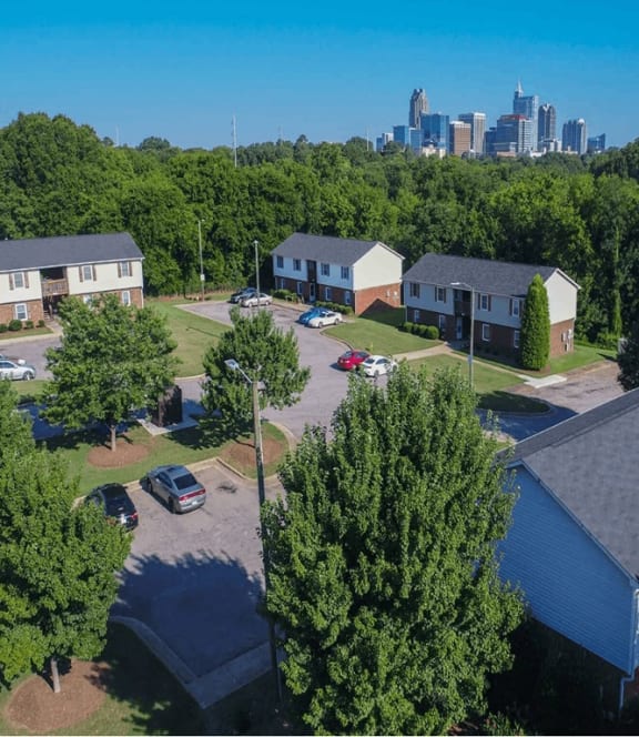 a cluster of houses with a city skyline in the background at Trails Corner Apartments, North Carolina, 27610