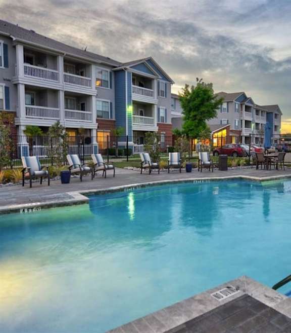 A swimming pool in front of apartment buildings. at Haven at Lewisville Lake Apartments, Lewisville, Florida