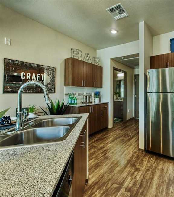 A kitchen with a sink, refrigerator, and a counter. at Craft at Gilbert and Baseline Apartments, Arizona