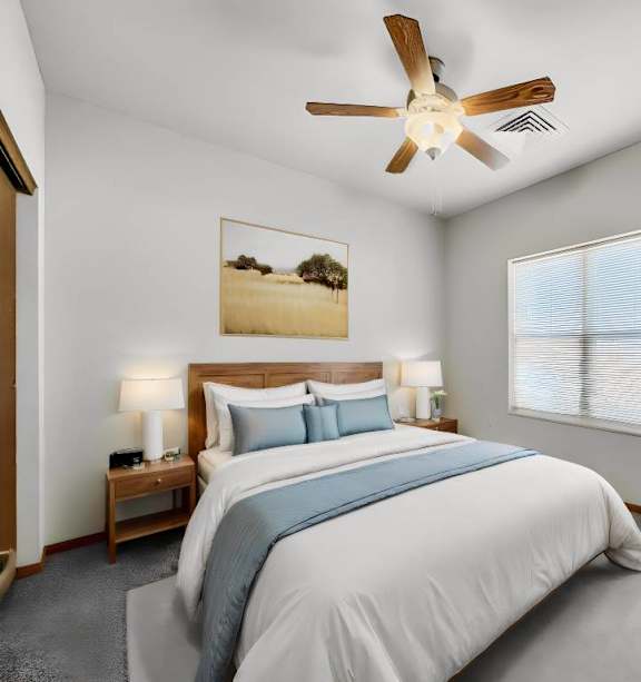 A bedroom with a large bed and a ceiling fan.at Cornerstone Commons, Johnston, 50131