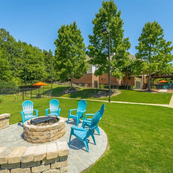a patio with blue chairs and a fire pit