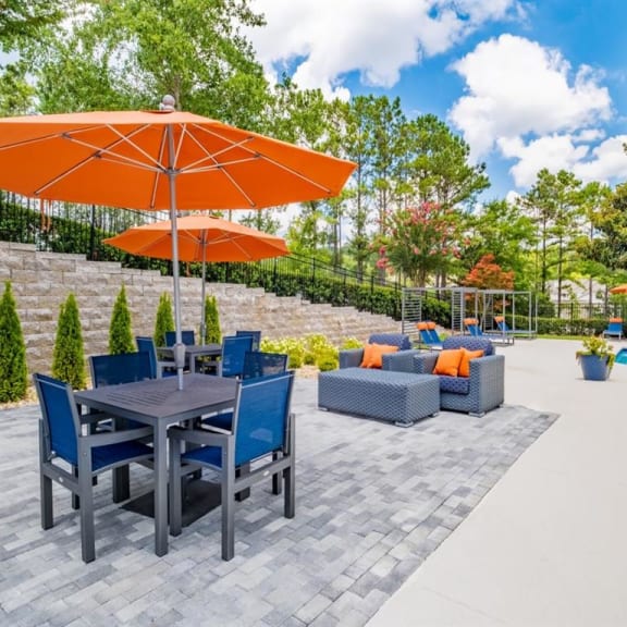 a patio with a table and chairs and an umbrella next to a swimming pool