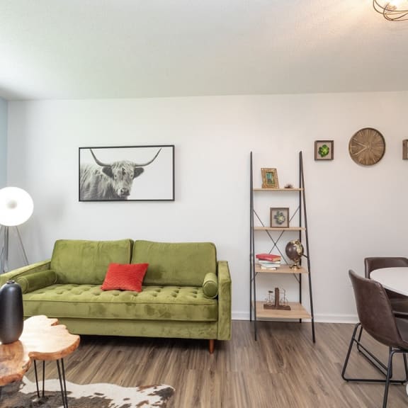 a living room with a green couch and a bull painting on the wall at Capital Flats & Magnolia Square Apartments, Raleigh, NC