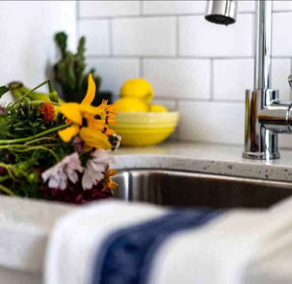 a kitchen sink with a bowl of lemons in the background