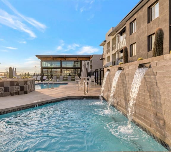 a pool with two waterfalls and a building in the background