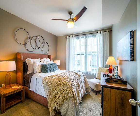 A bedroom with a queen-size bed, windows, and nightstands at Parkside at Firewheel Apartments. 