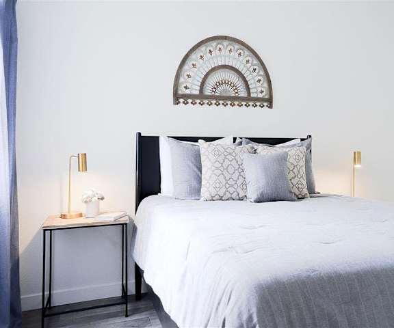 A bedroom with a queen-size bed, a dresser, decorations, window, and nightstands at Hillside Village. 