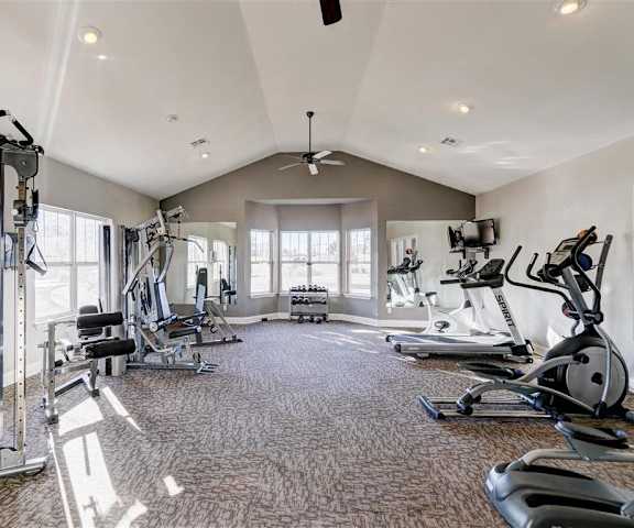 A gym with cardio machines, large windows, TVs, and weights at Residence at North Penn Apartment Homes. 