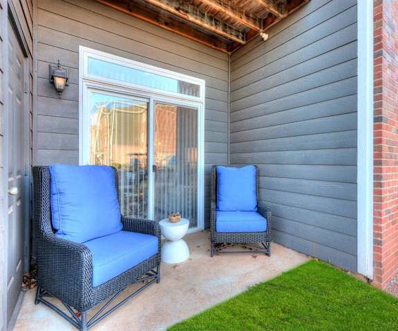 The outdoor private patio with grass and two plush outdoor chairs and a coffee table at Residence at North Penn Apartment Homes. 