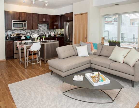 A modern living room with a grey sofa and a glass coffee table.