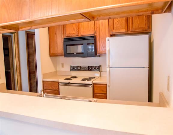 A kitchen with a white refrigerator and black microwave.