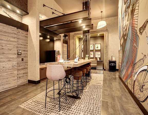 A modern kitchen with a bar area and a mural of a bicycle on the wall at Coda on H Apartments, District of Columbia