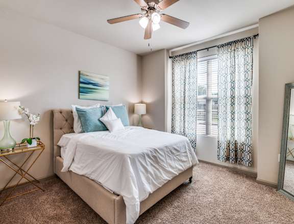 A bedroom with a large bed and a ceiling fan.
