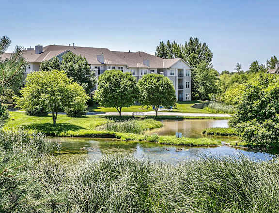A large white building with a pond in front of it at Autumn Grove Apartments, Omaha, 68135