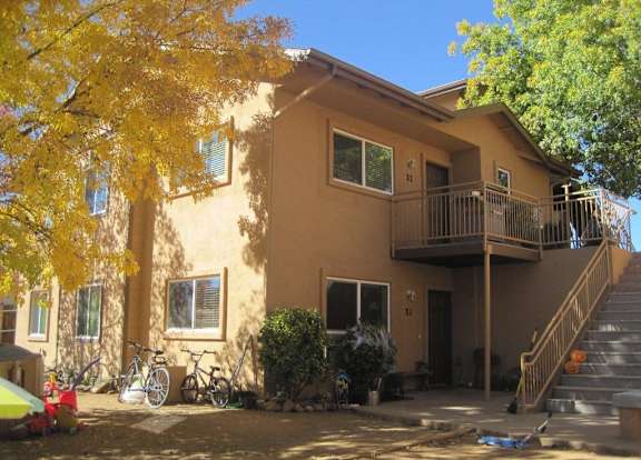 A yellow tree is in front of a tan house.