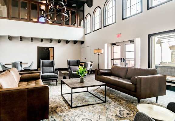 A living room with brown leather furniture and a chandelier.
