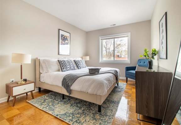 A bedroom with a large bed and a wooden floor.