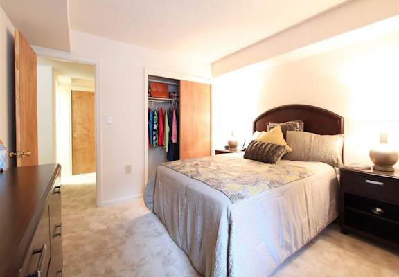 A bedroom with a bed, nightstand, and closet.