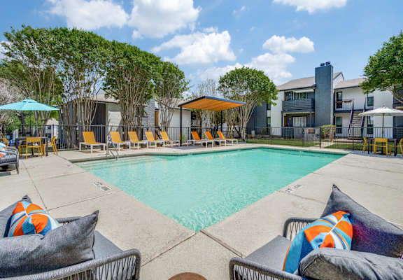 A pool area with lounge chairs and umbrellas.
