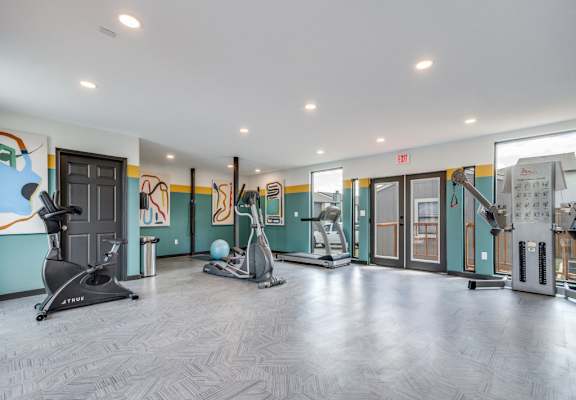 A gym with a variety of equipment including a treadmill, stationary bike, and weight machines.