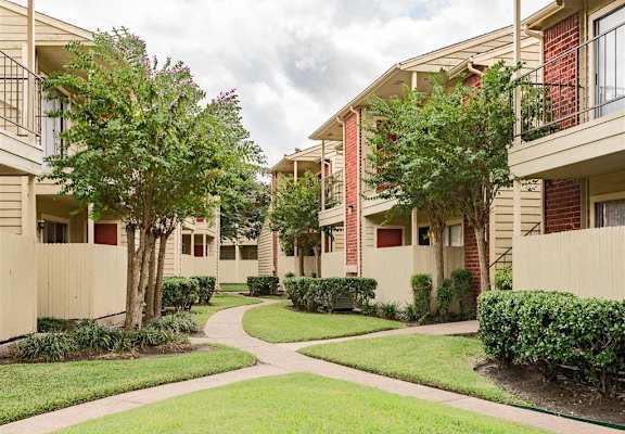 an apartment building with walkways and grass and trees