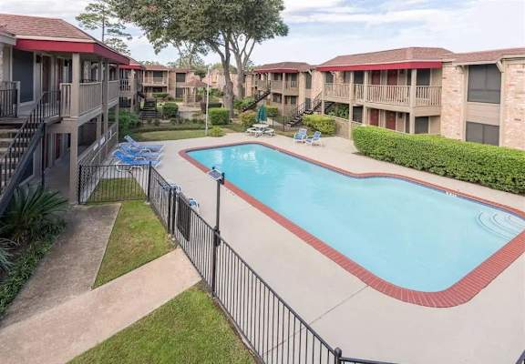 a swimming pool with a fence around it in front of an apartment building