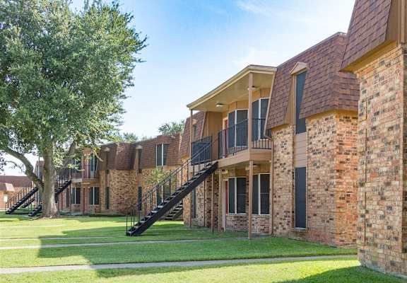a row of brick apartment buildings with grass and a tree