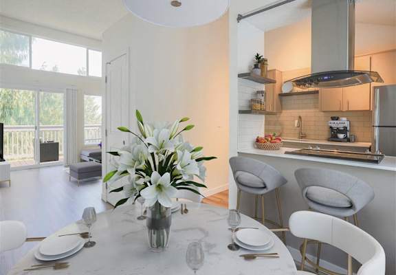 A kitchen with a table set for two with a vase of flowers on it.
