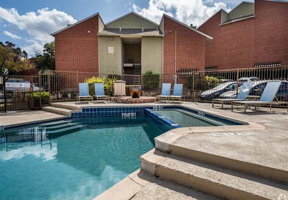 A swimming pool in front of a building with a red brick exterior. at Wildwood Apartments , Austin, 78752