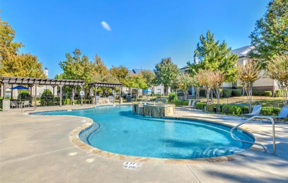 a swimming pool with trees and a building in the background at The Atlantic Mansfield, Mansfield, Texas