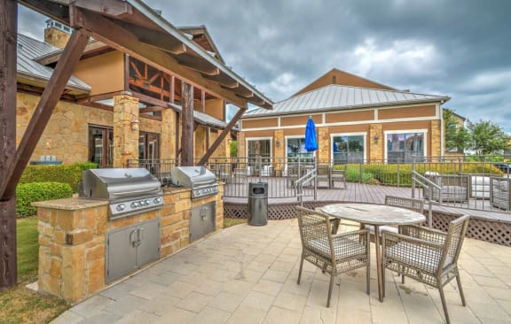 a patio with a table and two grills in front of a house at Village of Hawks Creek, Westworth Village, TX