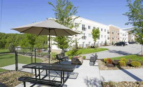 a picnic table with an umbrella in front of a building  at The Reserve on Washington, Naperville