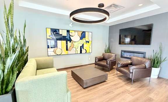 A living room with a green couch, brown leather couch, and a TV mounted on the wall.