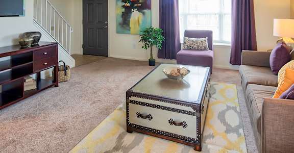 A living room with a couch, coffee table, and a painting on the wall.