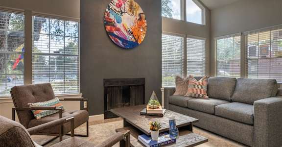 A living room with a fireplace and a large painting on the wall. at Wildwood Apartments , Austin, 78752