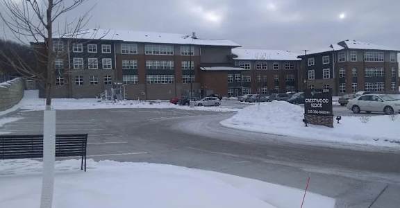 A snowy parking lot in front of a brick building.
