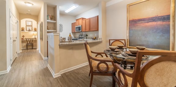 a dining area with a table and chairs and a kitchen in the background at Rose Heights Apartments, North Carolina, 27613