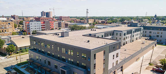 a large gray building with a gray roof and a city in the background at The Landing at 1001 NP, Fargo, North Dakota 58102