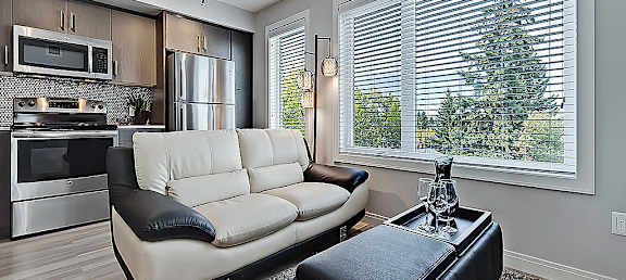 A modern kitchen with a white couch and a black ottoman.