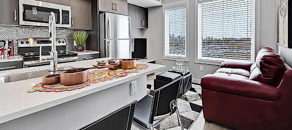 A modern kitchen with a red couch and black chairs.