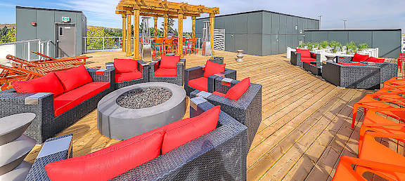 A wooden deck with red and black furniture and a fire pit.