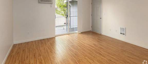 A room with wooden floors and white walls, featuring a sliding glass door.
