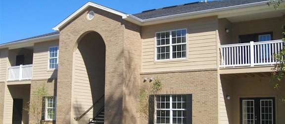 A beige building with a balcony and a staircase at Arbours at Ensley Apartments, Pensacola