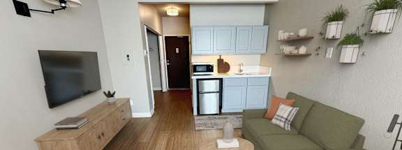 A living room with a couch, a television, and a kitchen area in the background.
