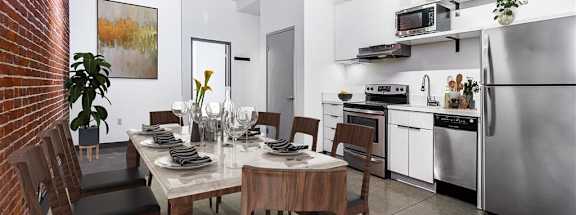 a dining room with a table and chairs and a kitchen in the background